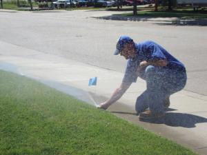 a Euless TX sprinkler repair tech marks a pop up head with an optimization flag